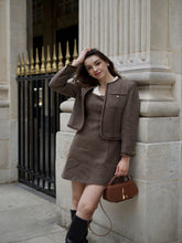 A lady wears a brown jacket.